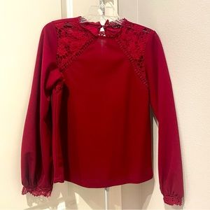 Wine colored top with lace details at the collar and sleeves